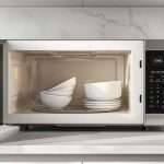 Посуд зі скла та кераміки в мікрохвильовій печі на домашній кухні